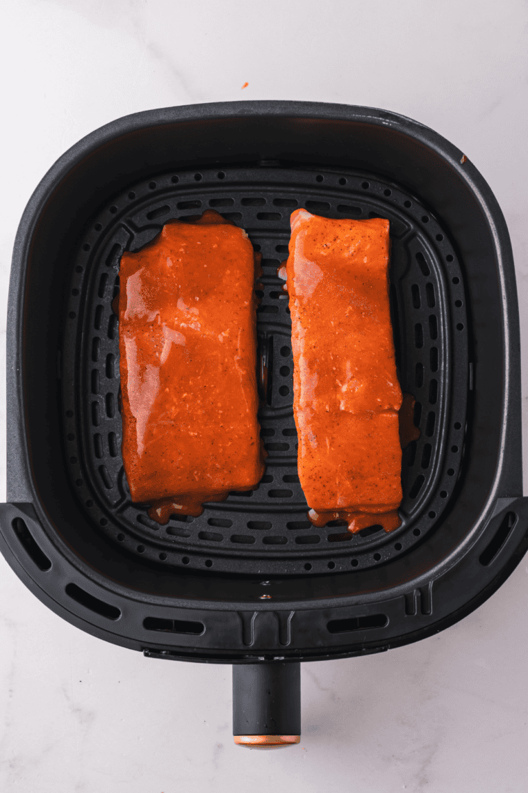 Salmon fillets placed skin-side down in the air fryer basket, set to cook at 400°F for 8-10 minutes.