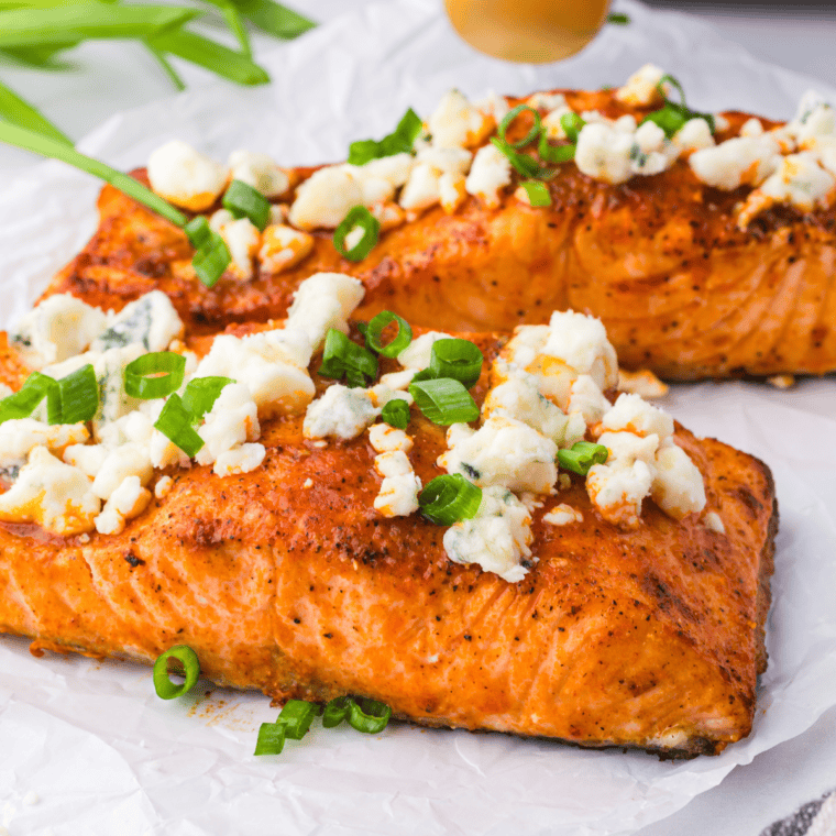 Spicy Air Fryer Buffalo Salmon fillet garnished with fresh herbs, served on a white plate.