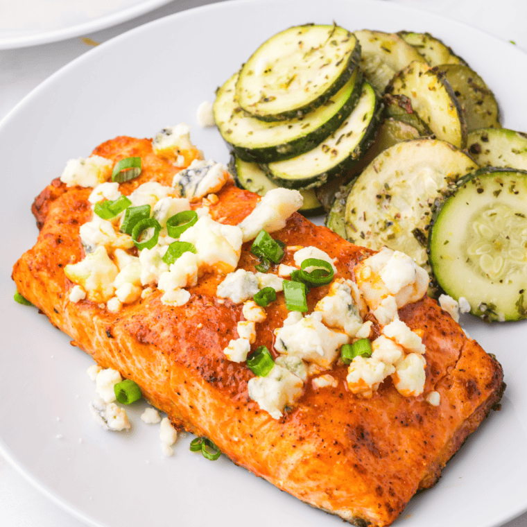 Air Fryer Buffalo Salmon fillet coated in spicy buffalo sauce, garnished with herbs on a plate.