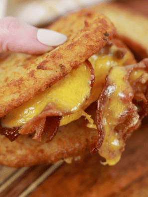 Crispy Air Fryer Hash Brown Breakfast Sandwich stacked with egg, cheese, and sausage, served on a wooden board.