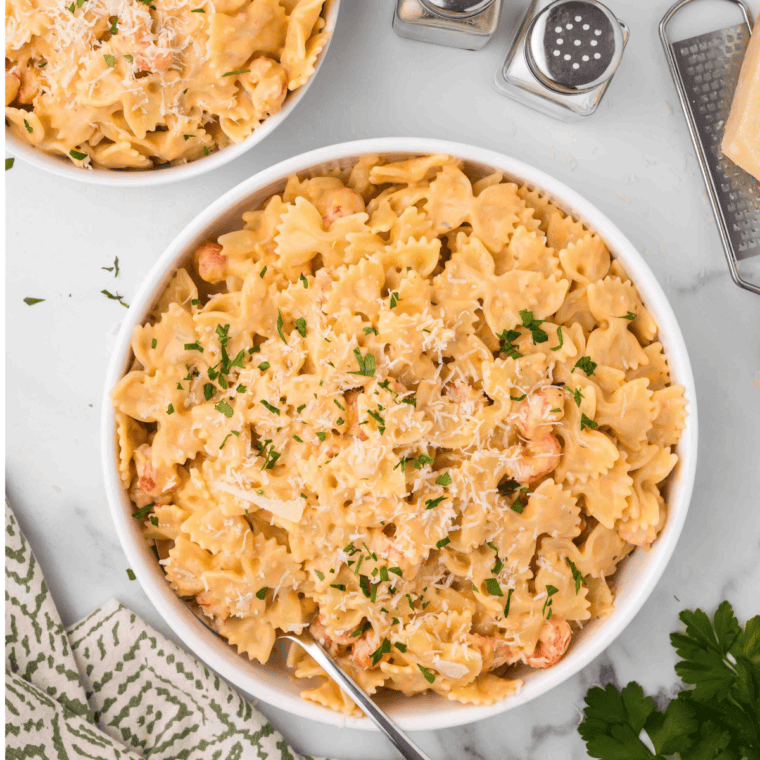 Creamy lobster bisque pasta topped with air fryer lobster chunks, served in a bowl and garnished with herbs.