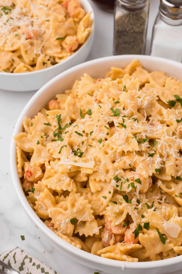 Air Fryer Lobster Bisque Pasta served in a bowl, topped with lobster tails, shaved Parmesan cheese, and fresh parsley.