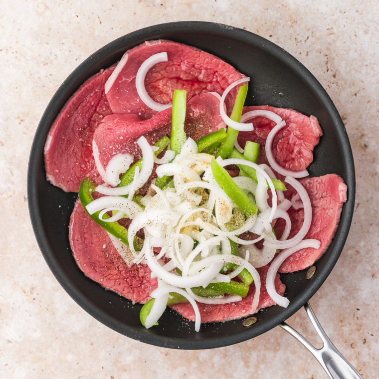 Sautéing thinly sliced beef, bell pepper, and onion in a skillet with olive oil and seasonings until browned and tender.