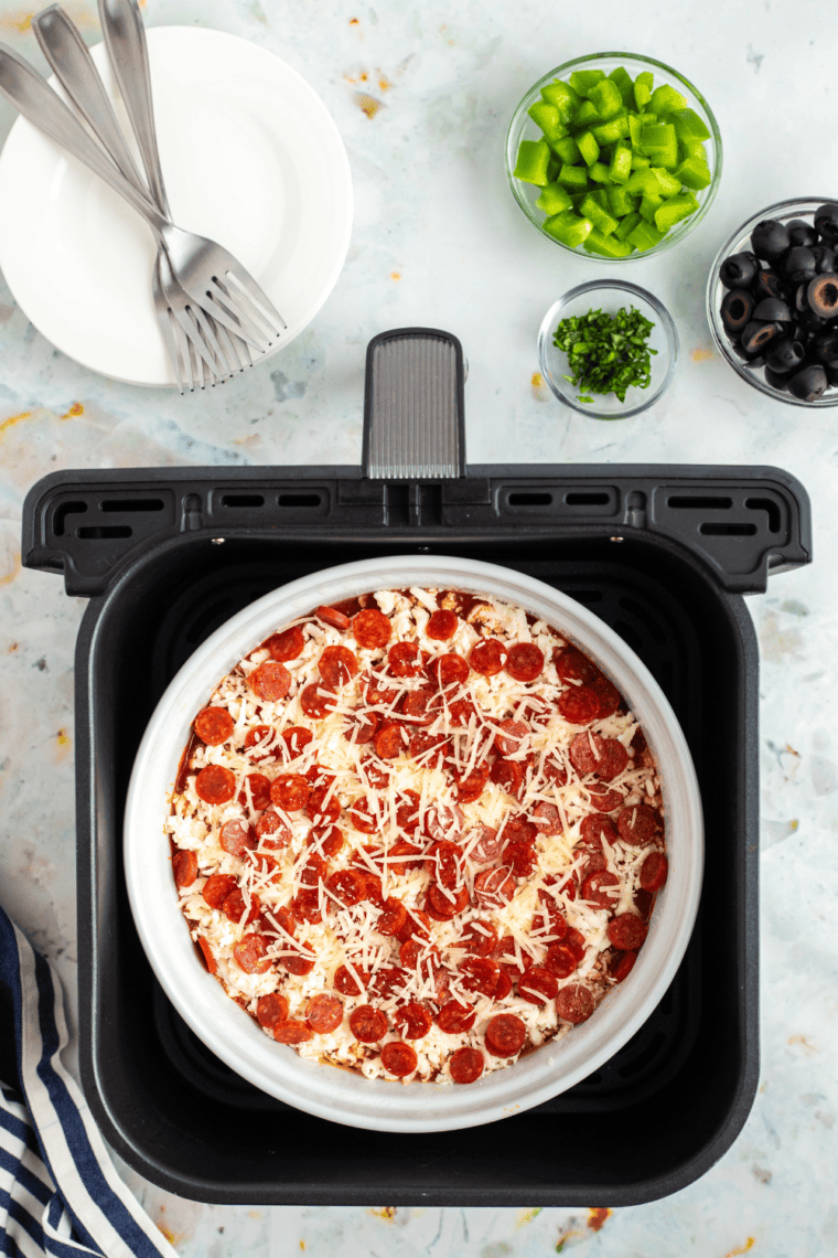 Pierogy pizza casserole in the air fryer basket with bubbling melted cheese.