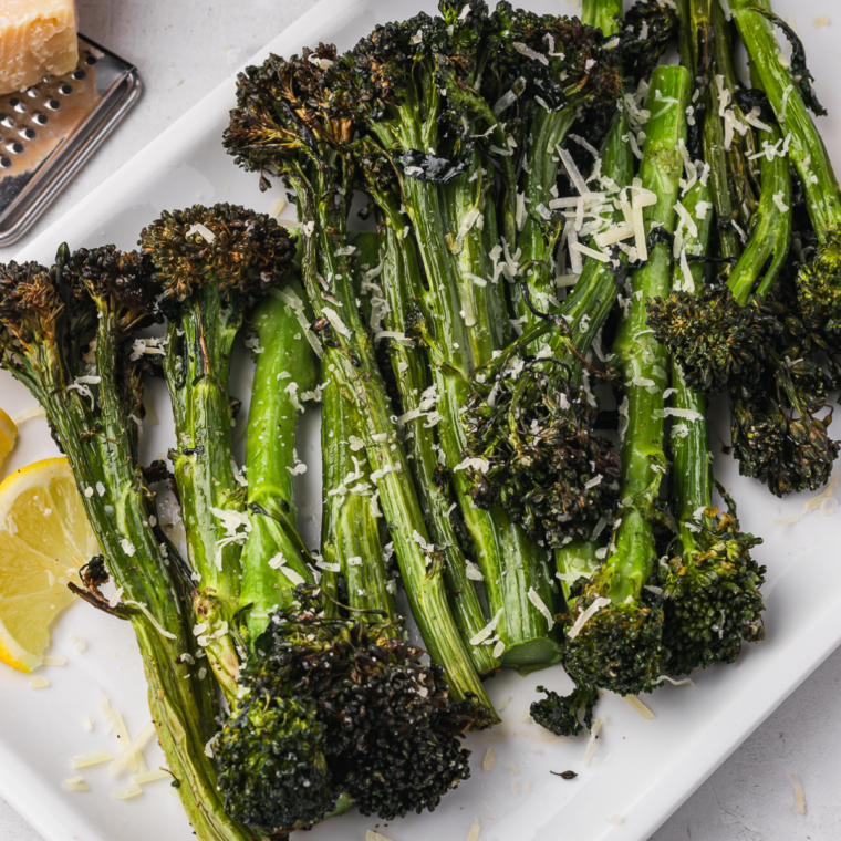Charred and crispy Tenderstem broccoli served fresh from the air fryer on a white plate.