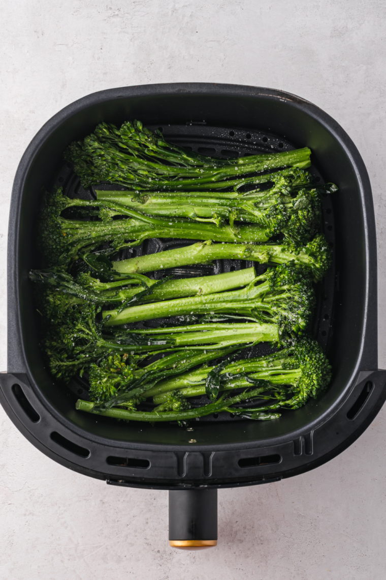 Seasoned tenderstem broccoli in a bowl, tossed with olive oil, salt, pepper, and garlic powder.