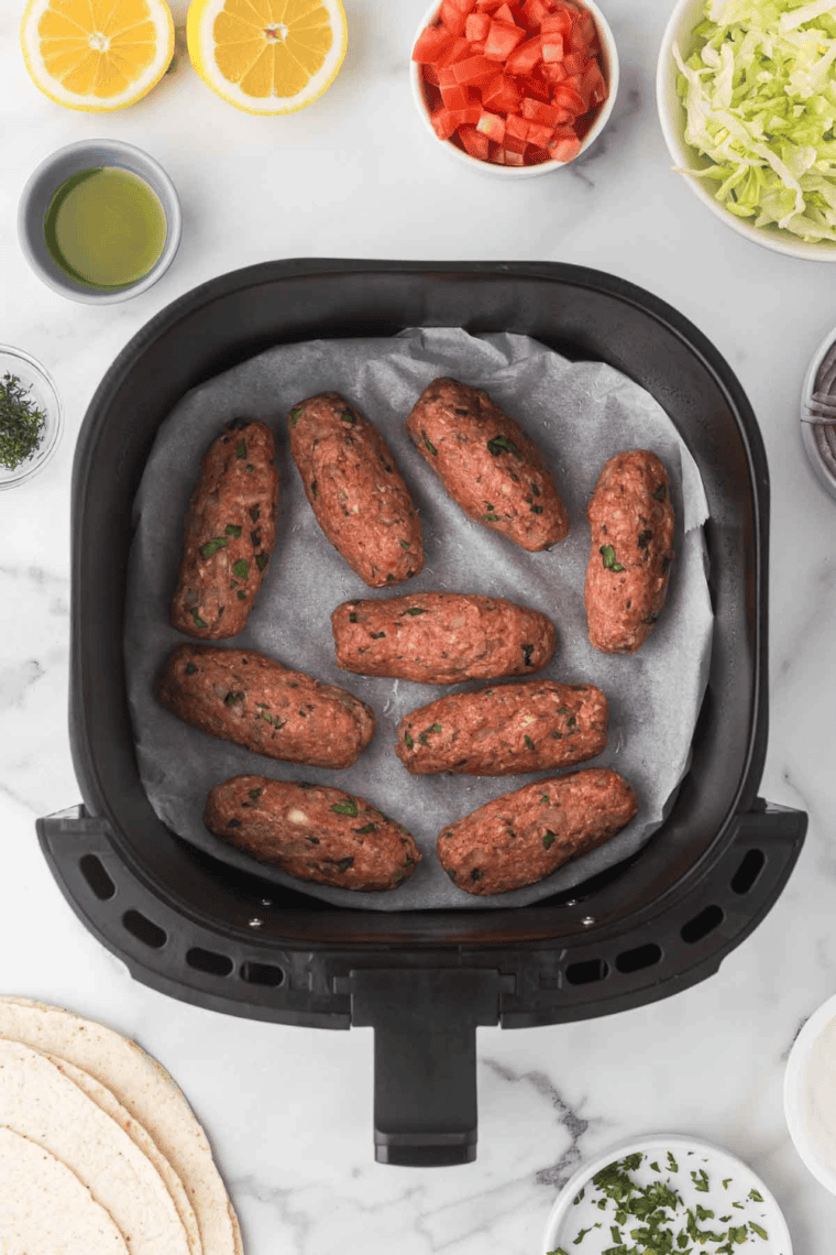 Lamb mixture cooking in the air fryer basket, set for 10–12 minutes, with pieces browning and crisping evenly.