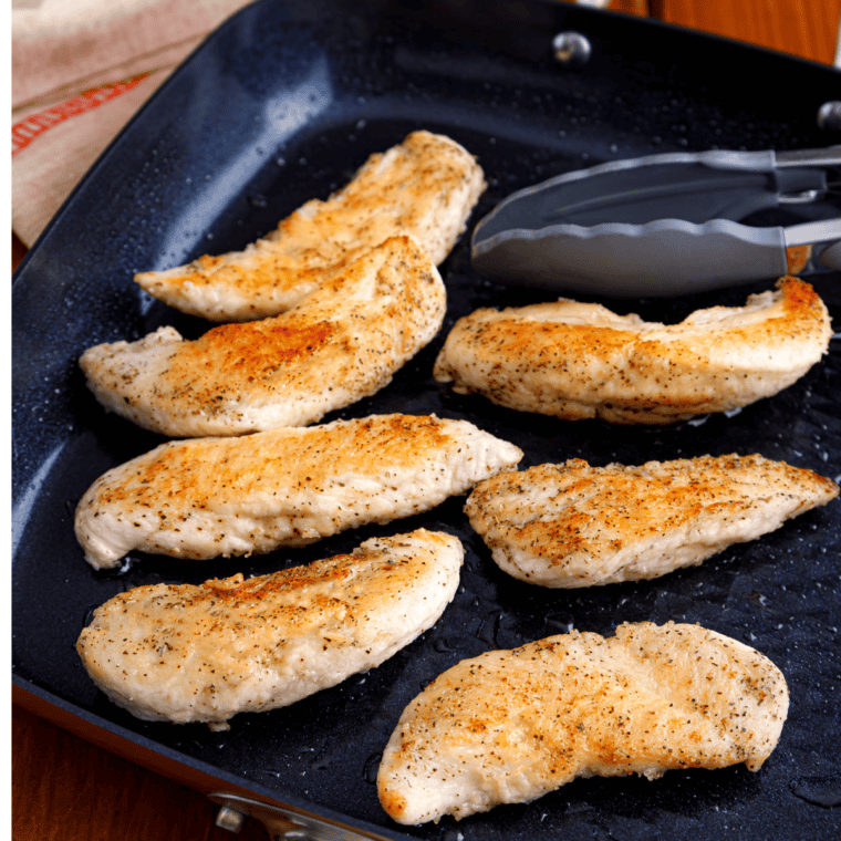 Golden brown chicken cutlets searing in a hot skillet with olive oil.