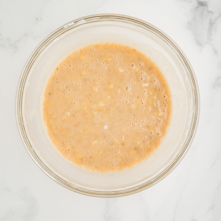 Mixing Greek yogurt, applesauce, vanilla, and eggs in a bowl until smooth and creamy.