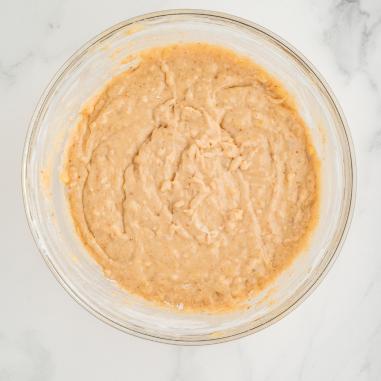 Whisking dry ingredients in a bowl before combining with wet banana bread batter.