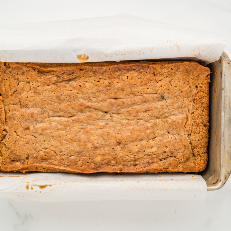 Sliced banana bread on a wooden board, showcasing its moist texture and golden-brown crust.