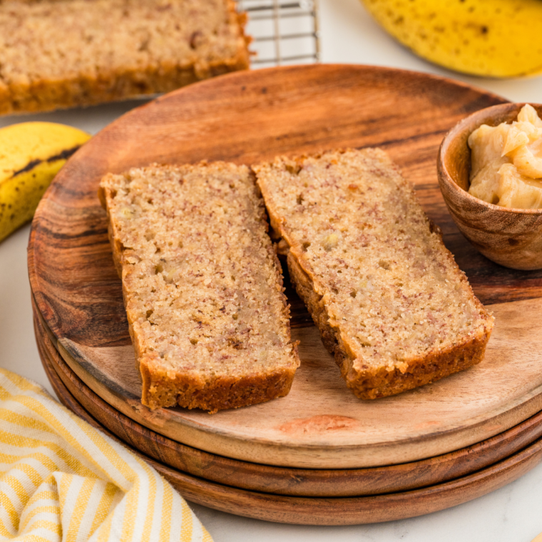 Sliced moist Weight Watchers banana bread on a wooden cutting board, showing its golden-brown texture.