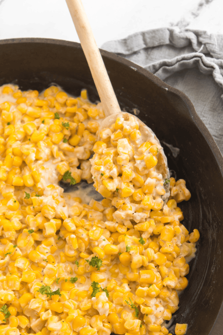Golden cast iron corn in a skillet, perfectly seared and seasoned with butter and spices.