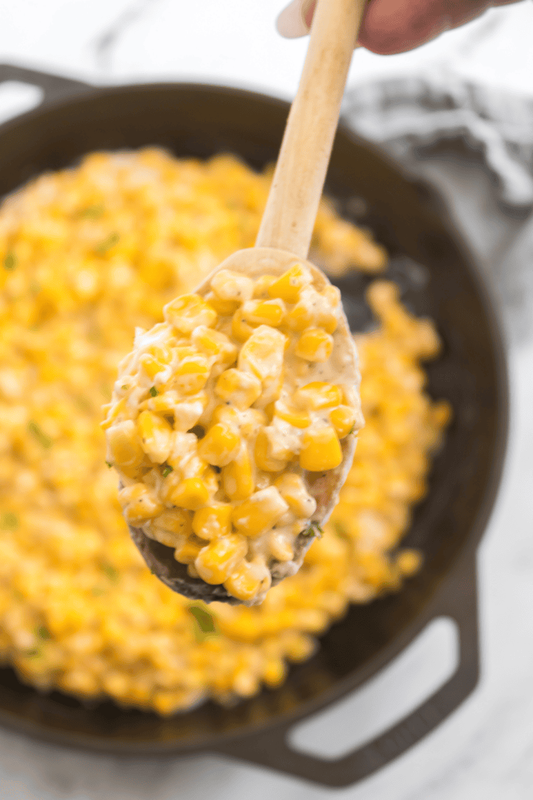 Corn on the cob being cooked in a hot cast iron skillet, ready to be served.