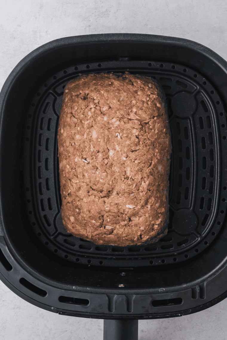 Shaping meat mixture into a loaf and placing it in the air fryer basket.