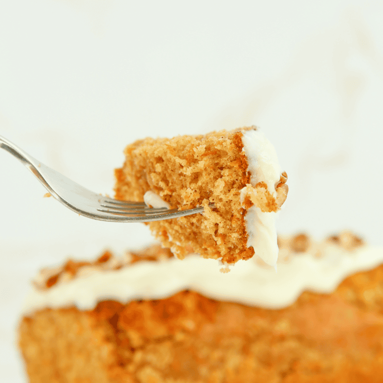 Moist slice of Copycat Cracker Barrel Carrot Cake with cream cheese frosting and chopped pecans on top.