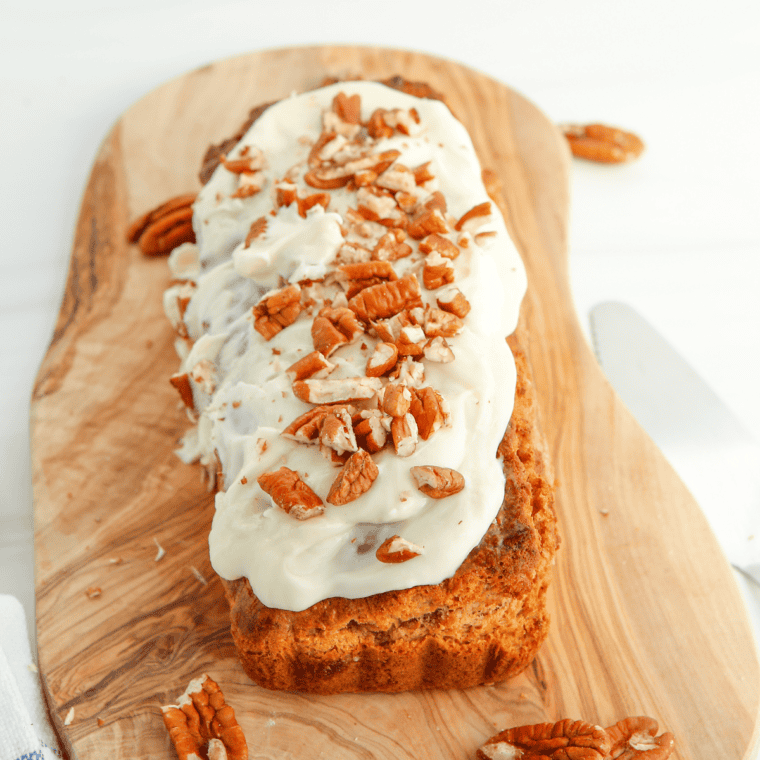 A slice of Cracker Barrel-inspired carrot cake topped with smooth cream cheese frosting and garnished with chopped pecans, served on a plate.