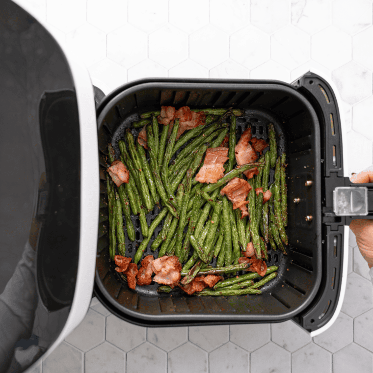 Green bean mixture in a parchment-lined air fryer basket cooking at 370°F, ready to be served as a warm, savory side dish