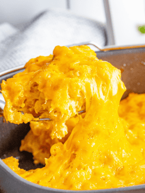 Bowl of creamy 3 cheese mac and cheese topped with melted cheese and herbs.