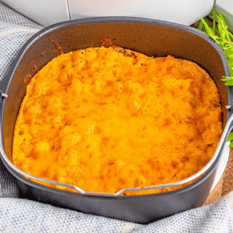 Bowl of creamy 3 cheese mac and cheese topped with melted cheese and herbs.
