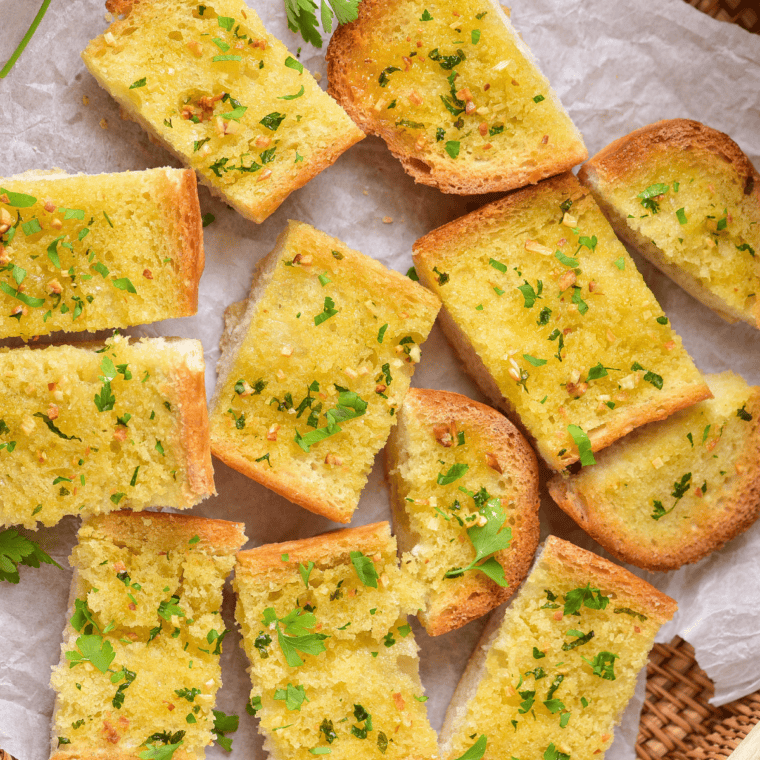 Plate of homemade garlic bread in bread basket, with homemade easy Garlic Bread Spread.