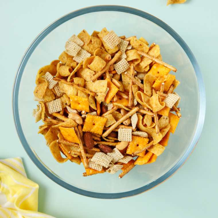 Large mixing bowl filled with Fritos, Chex cereal, pretzel sticks, peanuts, and cheese crackers ready to be mixed