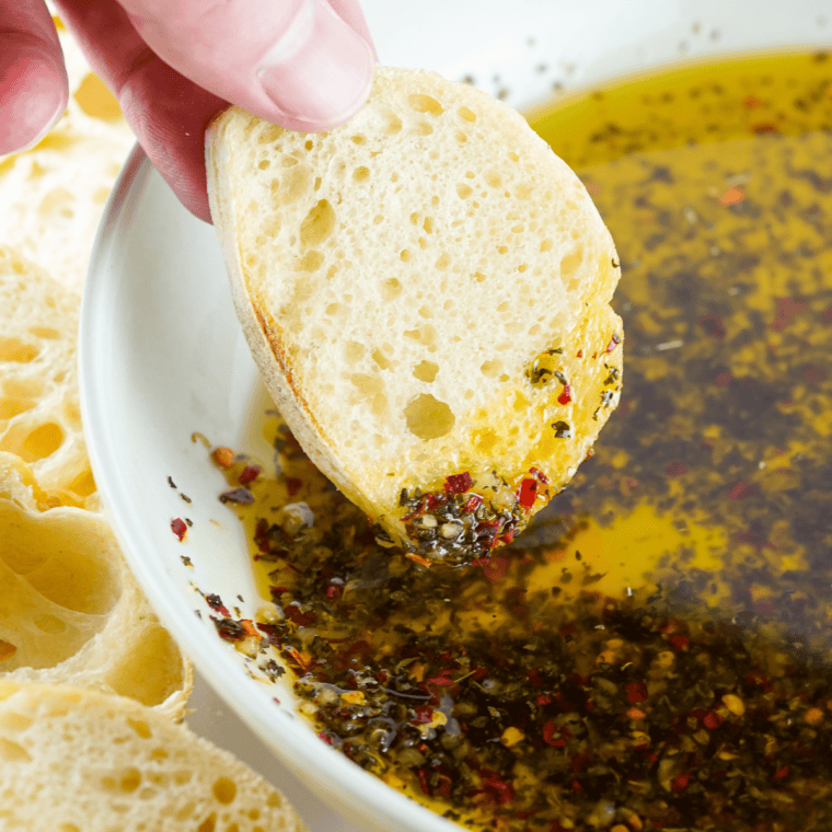 Bowl of Greek olive oil dip with oregano and garlic served with sliced crusty bread