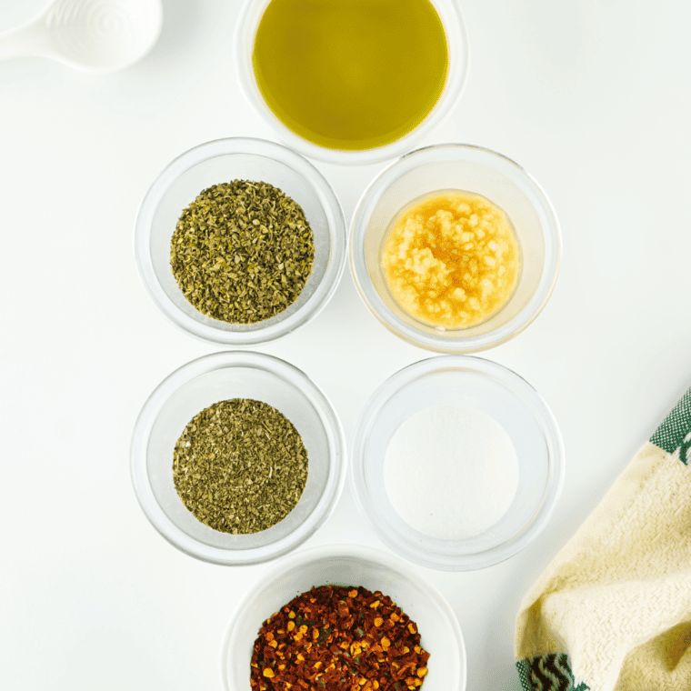 Ingredients for Greek bread dipping oil: olive oil, garlic, oregano, basil, lemon, and red pepper flakes
