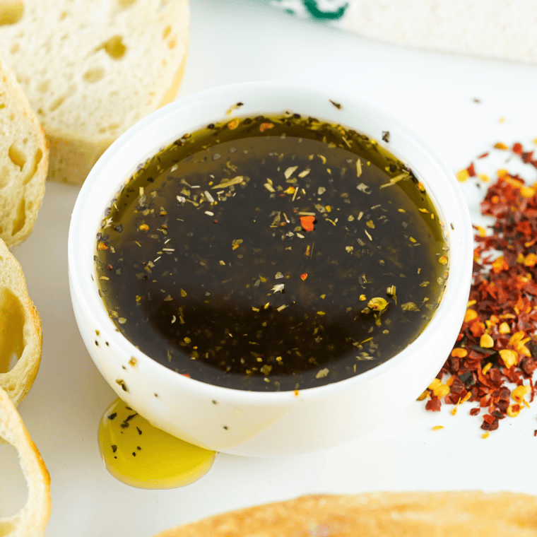 Greek herb and garlic dipping oil in a shallow bowl with crusty bread for dipping