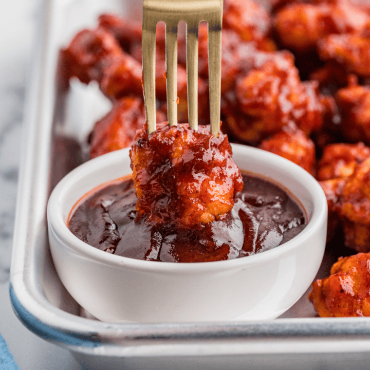 Homemade KFC honey BBQ sauce in a small bowl with a basting brush and grilled chicken in the background.