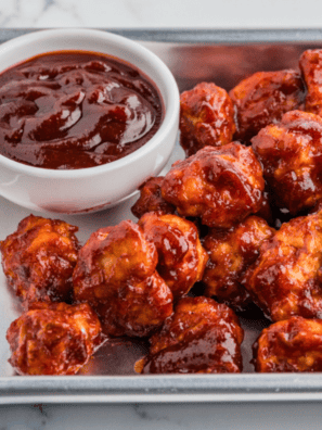 Small bowl of homemade KFC-style honey BBQ sauce with a brush and grilled chicken pieces nearby.