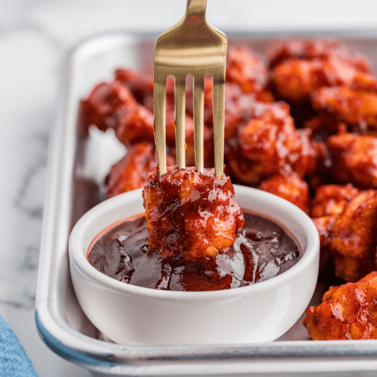 Thick, glossy homemade KFC-style honey BBQ sauce in a small bowl with a basting brush beside grilled chicken.