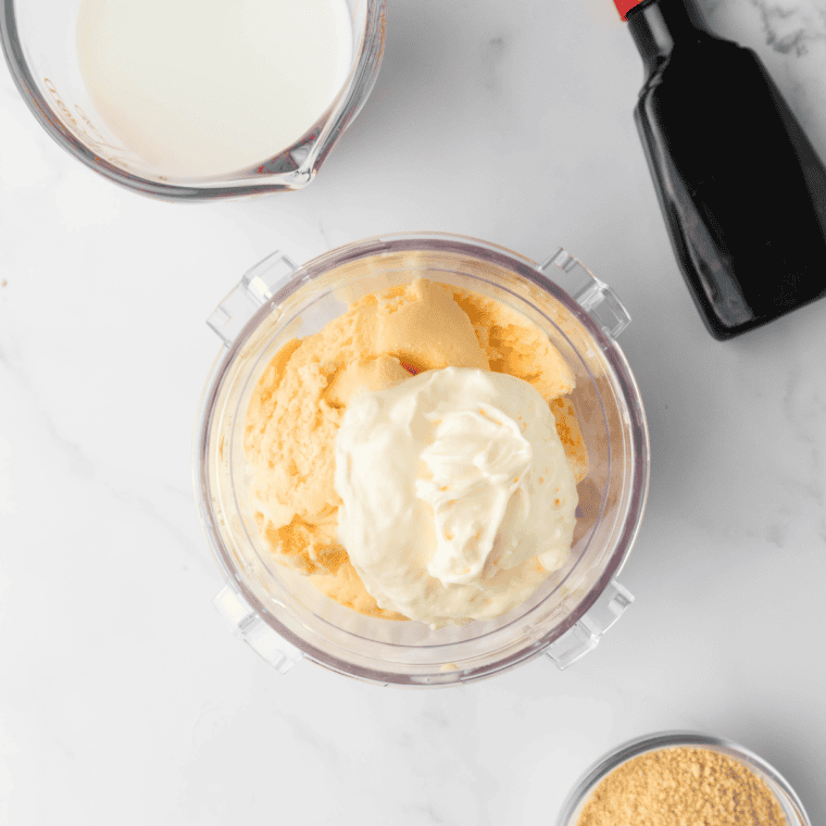 Combining ice cream, cream cheese, milk, and vanilla in a Ninja Creami pint container before blending into a creamy milkshake.