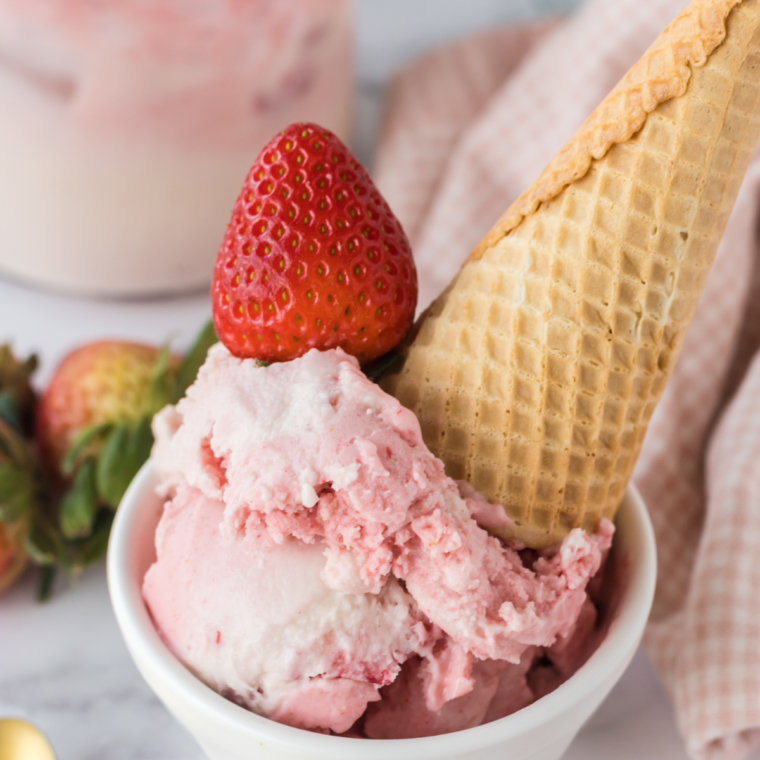 Creamy Ninja Creami dairy-free strawberry ice cream in a bowl with sliced fresh strawberries on top.