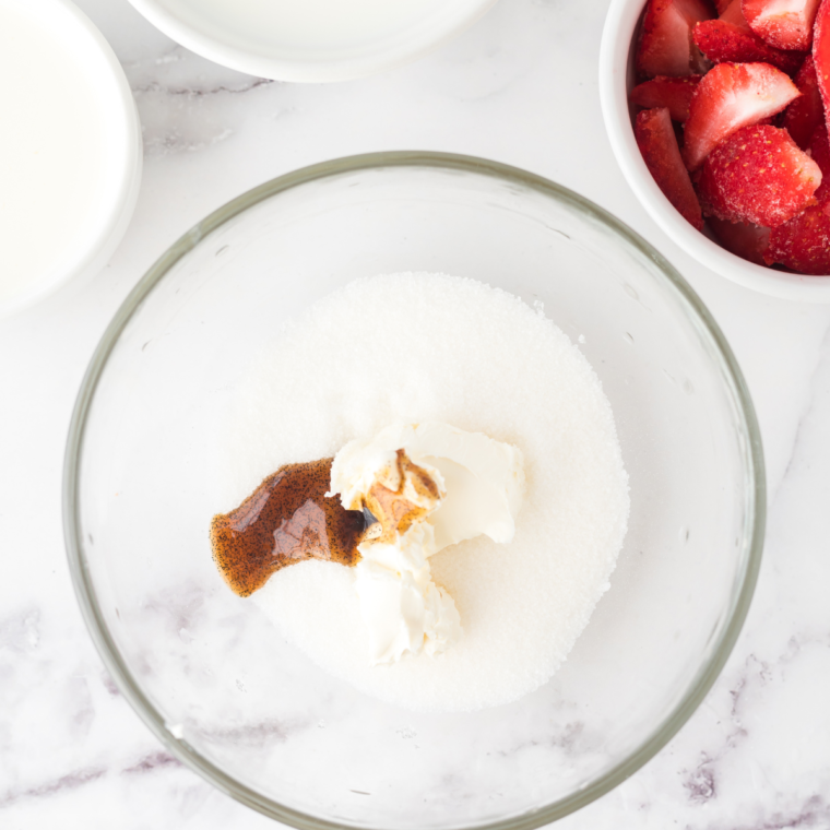 Blending vegan cream cheese, sugar, strawberry extract, coconut cream, and oat milk in a blender until smooth.