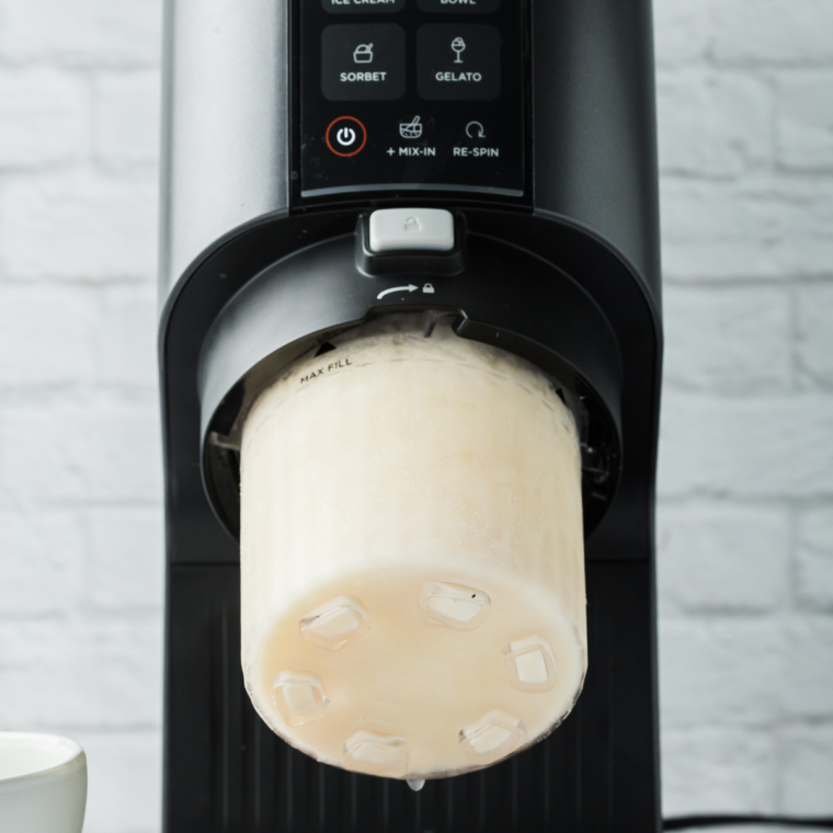 Placing a frozen pint into the Ninja Creami and selecting the Ice Cream setting.