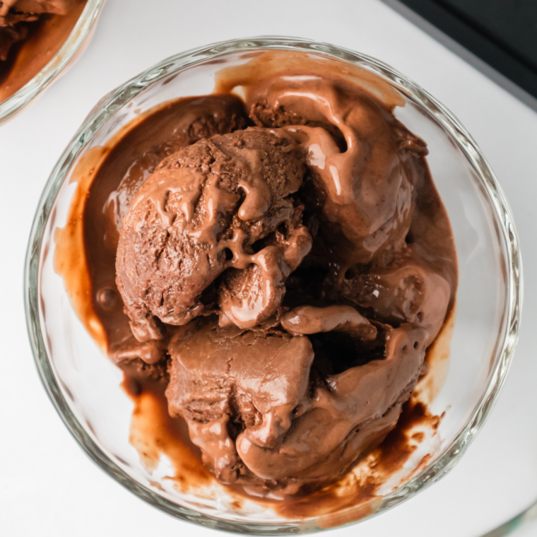 Creamy scoop of Ninja Creami frozen hot chocolate in a bowl, topped with whipped cream and chocolate drizzle.