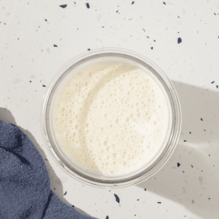 Mixture cooling to room temperature before being poured into a Ninja® CREAMi® pint container, sealed, and placed in the freezer for 24 hours.