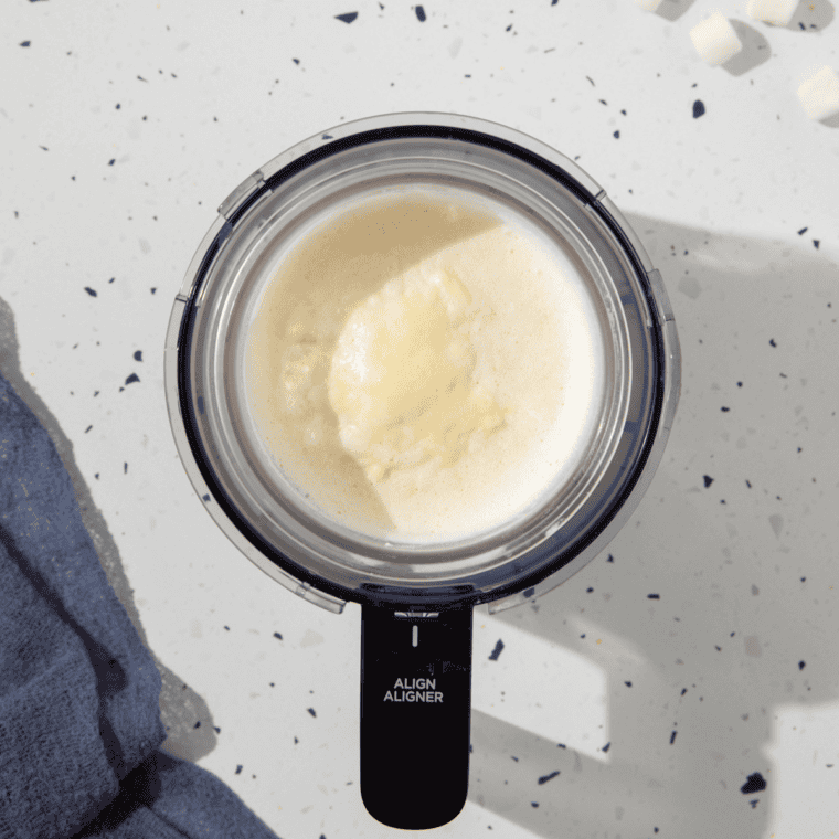 Pint container removed from the freezer and placed into the Ninja® CREAMi® machine, ready to select the 'Ice Cream' function.