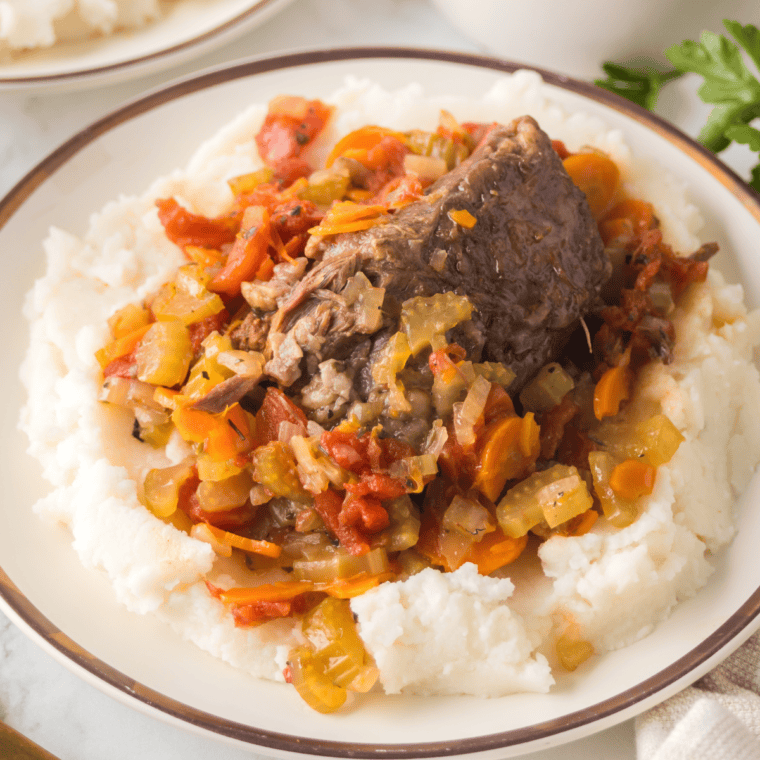 Ninja Foodi Beef Osso Buco with tender beef shanks in a flavorful broth, served with carrots, onions, and a rich sauce.