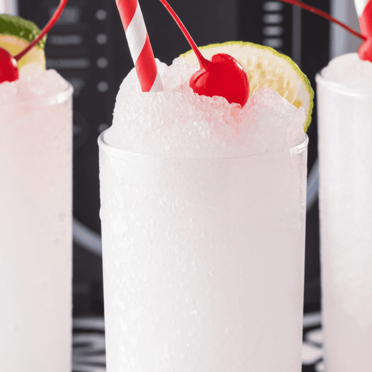 A vibrant red Ninja Slushi Cherry Slushie in a glass, garnished with fresh cherries and a straw.