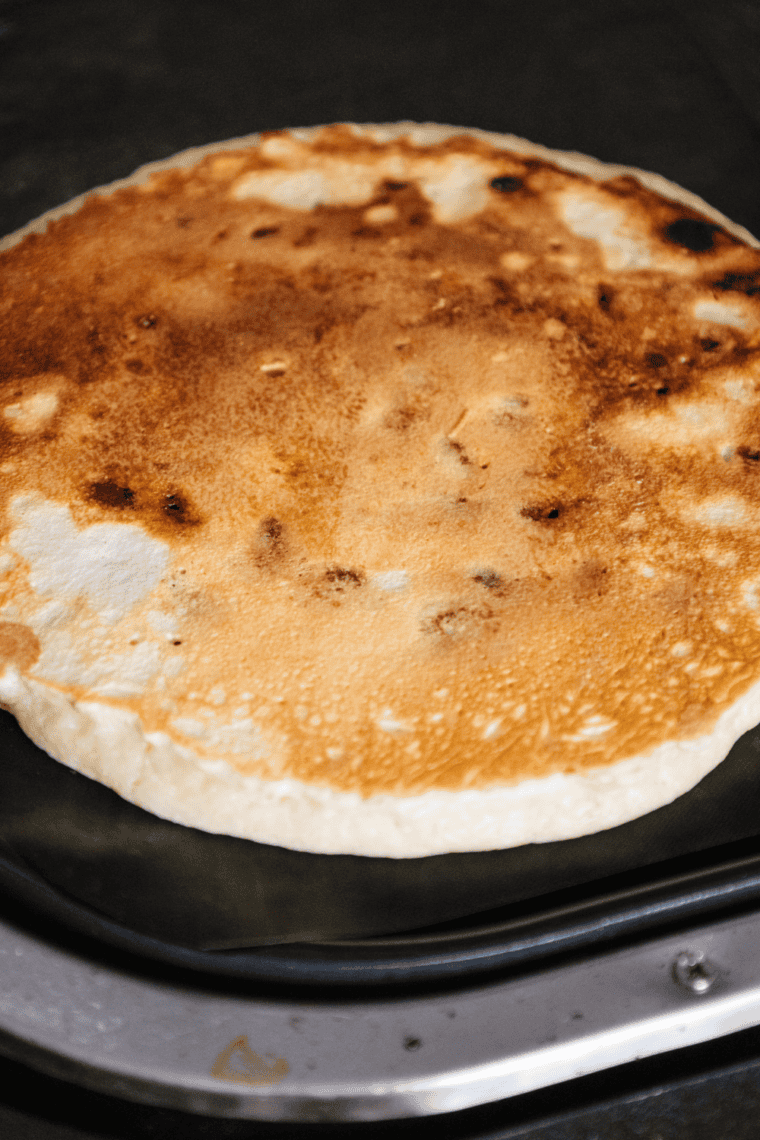 Golden, fluffy pancakes cooked on a Ninja Woodfire Grill, topped with syrup and fresh berries