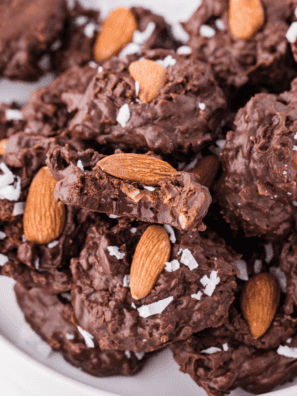 Close-up of Slow Cooker Almond Joy Chocolate Clusters made with melted chocolate, shredded coconut, and whole almonds, arranged on parchment paper.