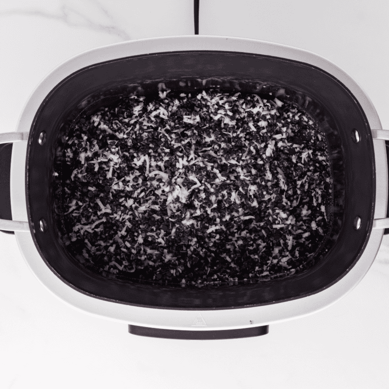 Slow cooker covered with lid, melting chocolate mixture being stirred every 15 minutes until smooth and fully melted.
