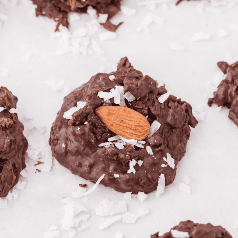 A batch of Slow Cooker Almond Joy Chocolate Clusters topped with coconut and almonds, arranged on a parc
