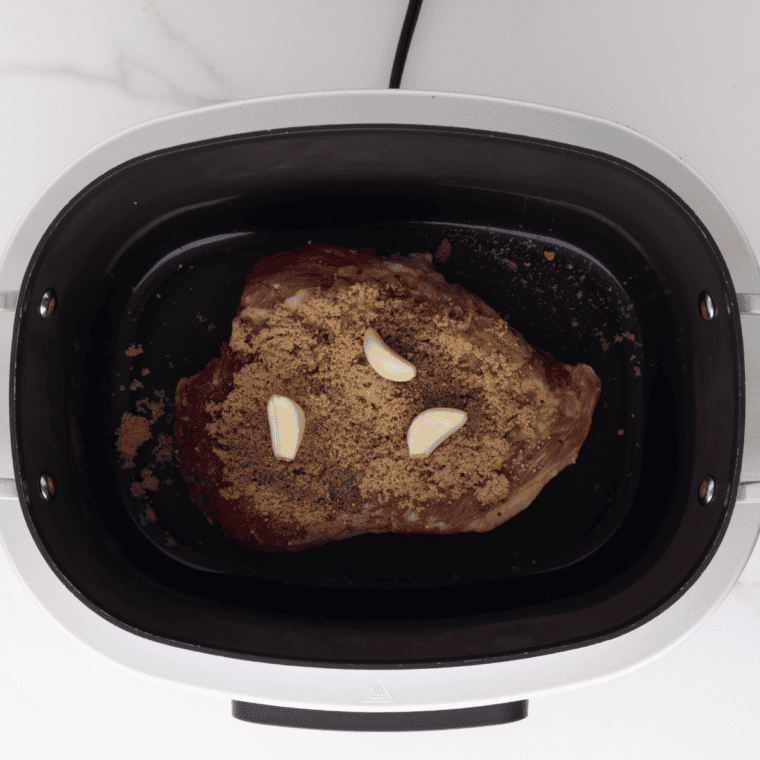 Spice-rubbed beef brisket in a slow cooker, coated with brown sugar, black pepper, and pastrami seasoning