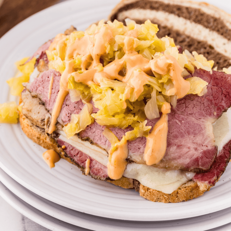 Sliced slow-cooked pastrami with a peppery crust on a wooden cutting board, ready for serving