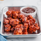 Jar of Sweet Honey Bourbon BBQ Sauce with a basting brush and fresh ingredients nearby.