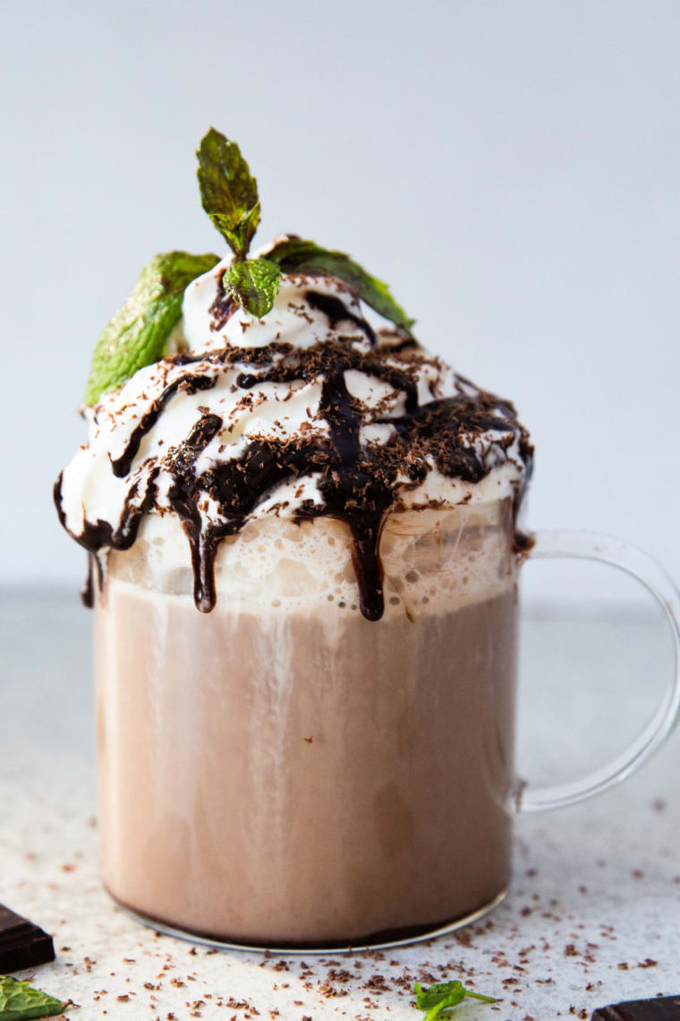 Homemade café mocha latte in a mug, topped with frothy milk and a sprinkle of cocoa.