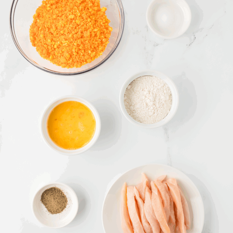 Chicken strips, flour, eggs, and crushed Cheetos laid out for the recipe